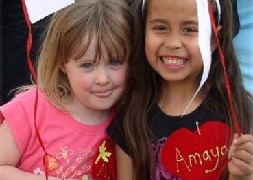 Two young girls attending an Ele's Place event wearing hearts in memory of someone who has died that was important to them.